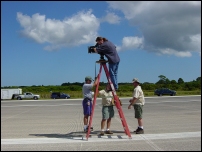 Director Todd Sims gets a shot from the center stripe of the Space Shuttle Landing strip at KSC in FL.  Also pictured (L to R), Sound Mixer Joe Hancock, Gaffer Bill Hennesy, and DP John Ames.